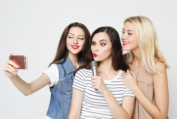 two beauty girls with a microphone take selfie with smartphone