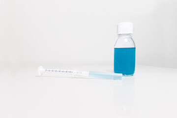 medicinal syrup of blue color with a dispenser on a gray background. Selective focus. oral syringe...