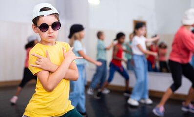 Portrait of preteen boy breakdancer in dance studio with dancing children in background..