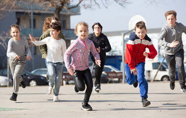 Obraz premium Kids spending time together outdoors running on square at warm spring day