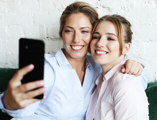 mature mother and her daughter making a selfie using smart phone