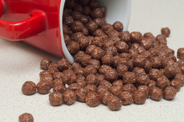Ready breakfast made of chocolate flakes poured from a red mug on the table