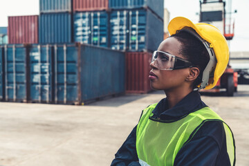 Young African American woman worker at overseas shipping container yard . Logistics supply chain...