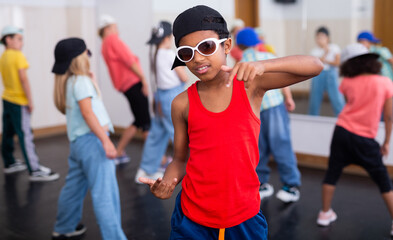 Portrait of preteen afro boy breakdancer in dance studio with dancing children in background..