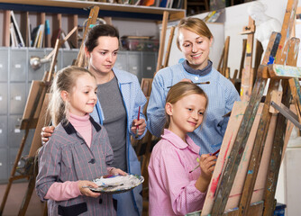 happy skillful young students looking at progress of fellow student during painting class