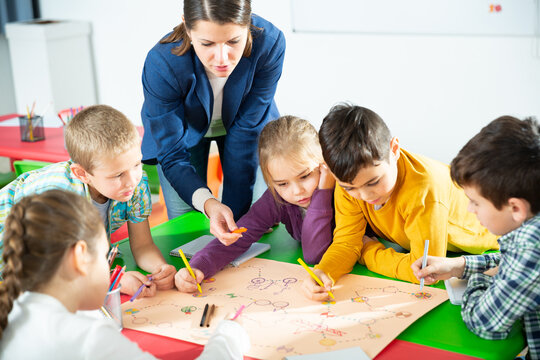 Teacher and collective of elementary age children draw together a board game. High quality photo