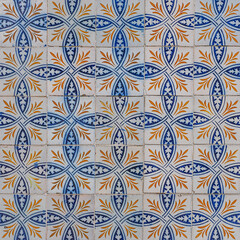Abstract ornamental background. Fragment of old building wall, with ornate glazed tiles. White tiles with blue orange painted decorations. Azulejos, traditional Portuguese art, for architecture design