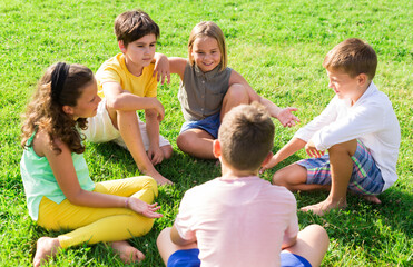Fototapeta premium Positive preteen childs, boys and girls, standing at a park in summer outside