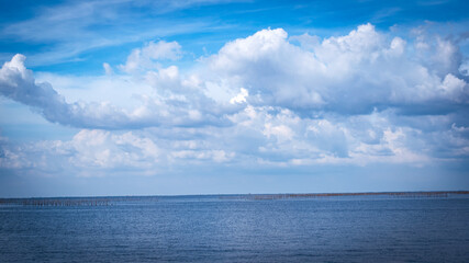 Naklejka na ściany i meble The vast sea with white clouds in the blue sky, beautiful nature.