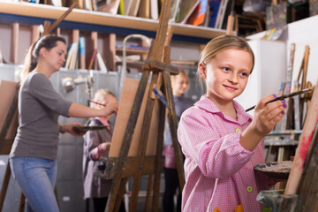 Fototapeta na wymiar Smiling italian schoolgirls diligently training their painting skills during class at art studio