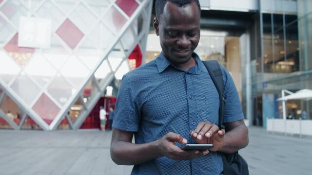 ppy African man typing on mobile phone walking in the urban street at Chengdu China