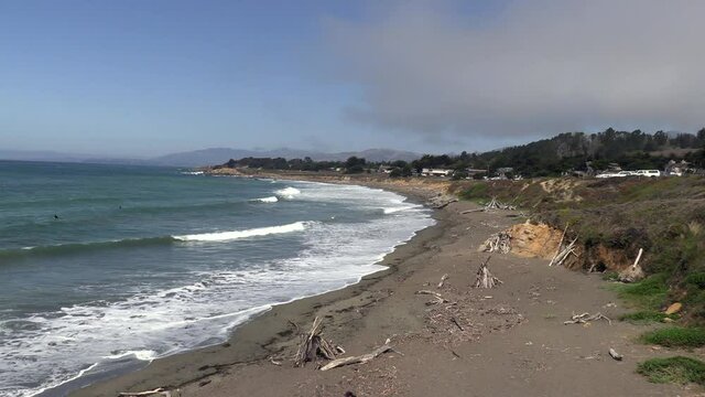 Pan of a Beach Near Cambria, California with Waves, Driftwood and a Family Playing in the Sand and a Curving Beach Shoreline