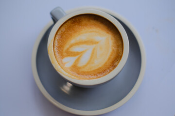 Cup of cappuccino coffee with flowers on table