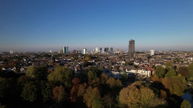 Autumn colors in the Lepelenburg park trees with the cityscape of Utrecht in the background where the scaffolded church tower rises above the urban Dutch city.