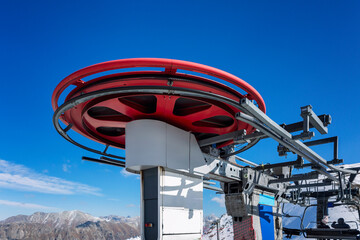 The driving mechanism of the lift high in the mountains on a clear day against the background of a blue sky. Winter sports and outdoor activities.
