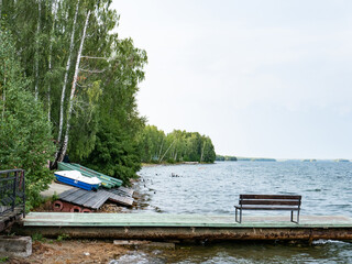 Naklejka na ściany i meble boats stand on the sandy shore. around trees, water, a pier. the beginning of summer. the swimming season is open. recreation centers are waiting for people, visitors, vacationers