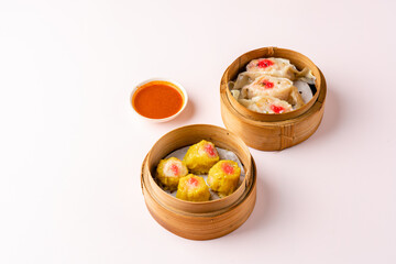 Top View of Assorted Chinese Dimsum in bamboo basket. Dimsum is a large range of small dishes that Cantonese people traditionally enjoy in restaurants for breakfast and lunch.