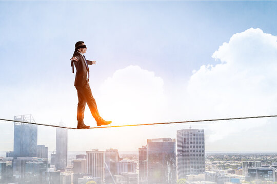Image of businessman balancing on rope. Risk concept