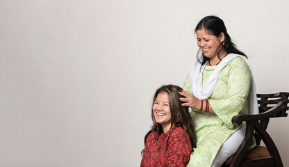 An indian girl getting her head massage by her mother, daughter and mother love for mother's day concept.