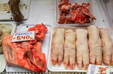 Raw pig trotters and neck with a price tag advertising the neck for sale at a local butcher shop in...