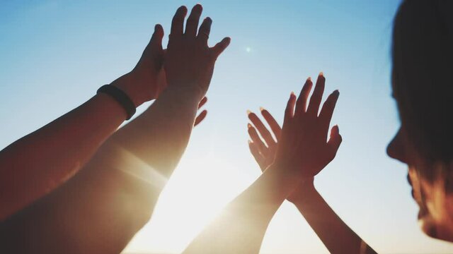 group of cheerful people together party pulling hands to the sun on the beach. teamwork. silhouette people party dancing recreation holiday. people fun music. pull their hands up. religion concept