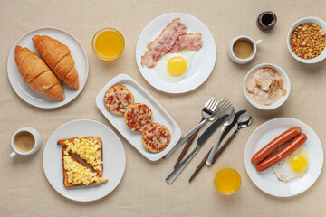 Hearty homemade family breakfast. Eggs, bacon, sausages, beans, croissants, toast and coffee on the table. Top View