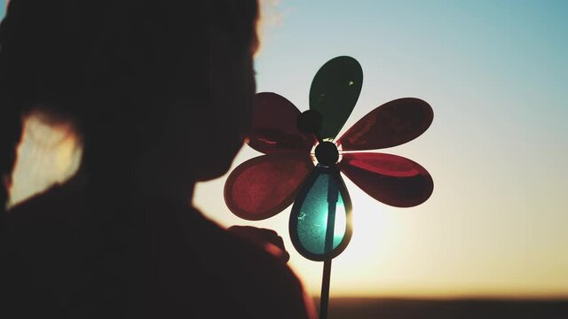 kid pinwheel. little baby girl silhouette play with windmill toy wind in the park. happy family kid dream concept. baby girl play toy pinwheel the glare of fun sunset the sun at in the park