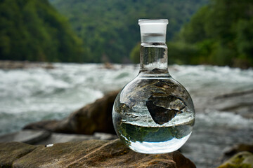 Bottle of drinking water on the shore of a mountain river.