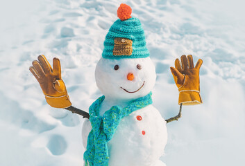 Snowman with hat and scarf in winter outdoor. Cute little snowman isolated on snow background.