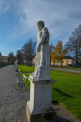 Old statues in line with benches on the Drottningholm island a color full autumn day in Stockholm