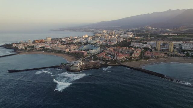 Playa de las Americas coastal skyline, Tenerife, dawn sunrise aerial drone orbit