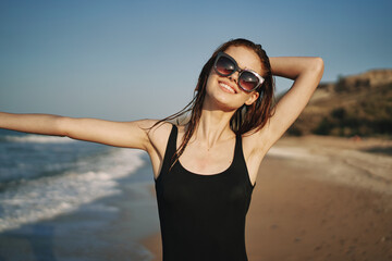 pretty woman in black swimsuit posing sun walking on the beach