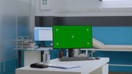Closeup of mock up green screen chroma key computer with isolated display standing on table in empty hospital office. Medical workplave with nobody in it ready for medicine assistance