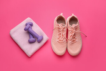 Dumbbells, towel and shoes on pink background