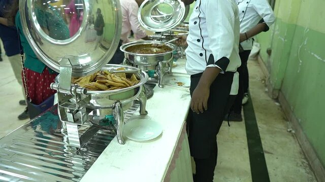 Slow motion cinematic shot of People group catering buffet food indoor in Indian wedding with meat. Buffet.