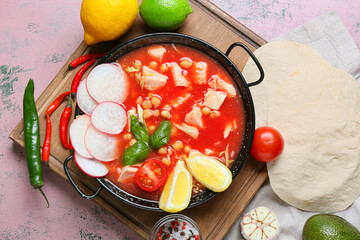 Frying pan with delicious homemade pozole soup on color background