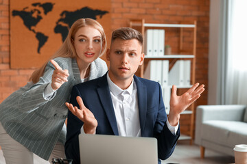 Male and female colleagues gossiping in office