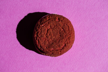 Closeup Image of One Separate Chocolate Macaron Placed Over Pink Background