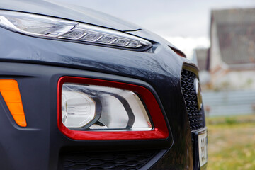headlight of modern prestigious car closeup. beautiful headlights of a car. dark gray color, red edging. part of the front, the car is unrecognizable. direction indicators on a sports car. side view