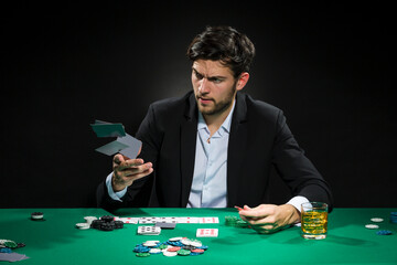 Casino Ideas and Concepts. Handsome Caucasian Young Pocker Player Staking and Betting To Win At Pocker Table With Chips And Cards.
