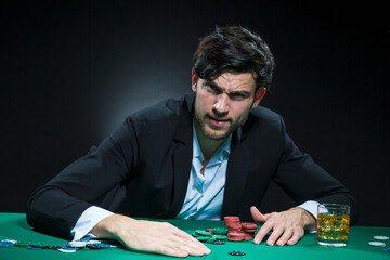 Nervous and Concentrated Handsome Caucasian Brunet Young Pocker Player At Pocker Table With Chips While Playing.