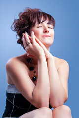 Obraz premium Portrait of Young Beauty Girl Demonstrating Short Curly Hairstyle as Fashion, Cosmetics and Makeup While Sitting And Dreaming Over Gray Background.
