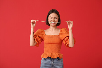 Funny young woman with chewing gum on color background