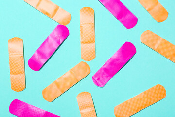 Pink and orange medical plasters on color background, closeup