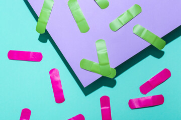 Pink and green medical plasters on color background