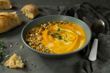 Creamy carrot pumpkin soup with seeds and baguette.