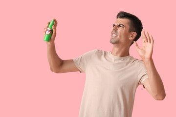 Young man with mosquito repellent on color background