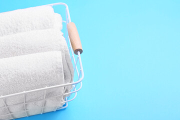 Basket with clean towels on blue background, closeup