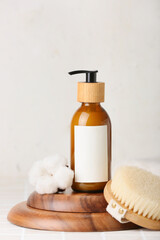 Composition with bottle of cosmetic product, massage brush and cotton flower on light background, closeup