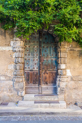 Fototapeta na wymiar Ancient door in a stone wall entwined with greenery. France